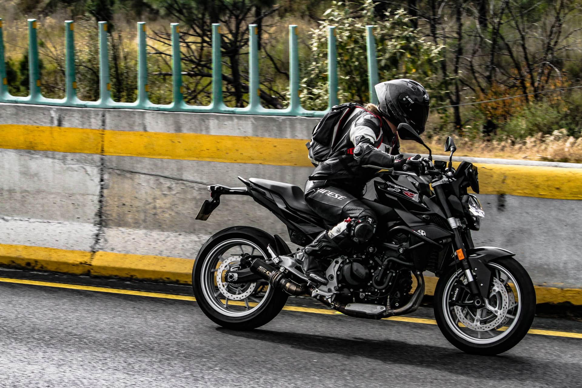 A motorcyclist in full protective gear riding on an open road